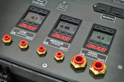 Närbild av en industriell kontrollpanel med digitala displayer och märkta röda och guldiga portar.
