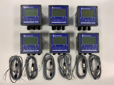 Sex TX2000 övervakningsenheter med digitala displayer, arrangerade i två rader, med lindade kablar under varje enhet.