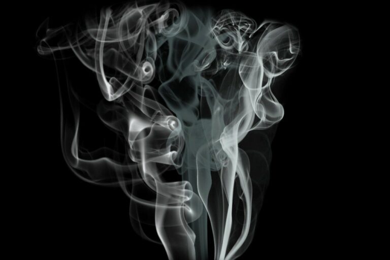 Vit rök som virvlar abstrakt mot en mörk bakgrund.