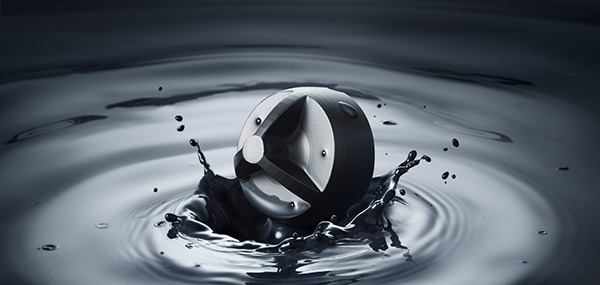 Ett svart sfäriskt föremål som stänker ner i mörkt vatten, skapar koncentriska cirkulära krusningar och droppar som sprider sig.